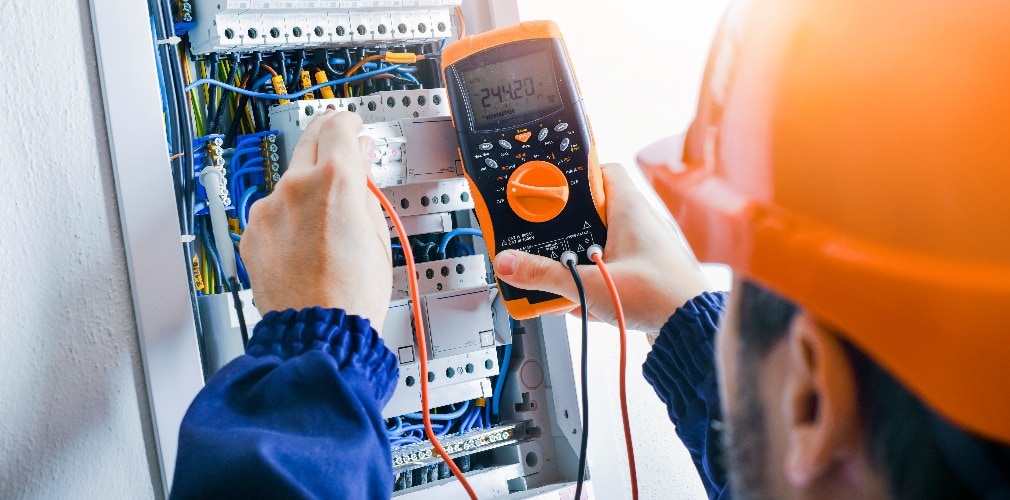 Electrician installing electric cable wires of fuse switch box.