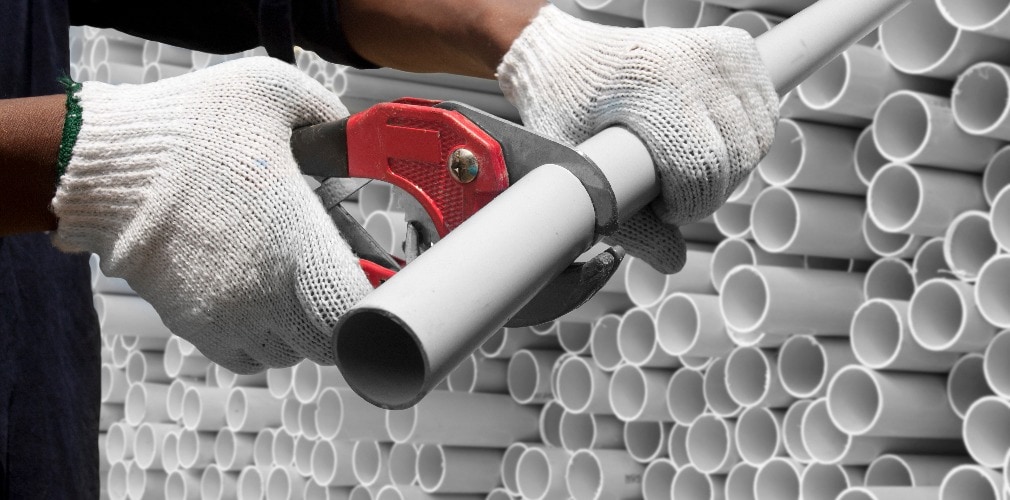 Worker cutting pvc pipe in construction site