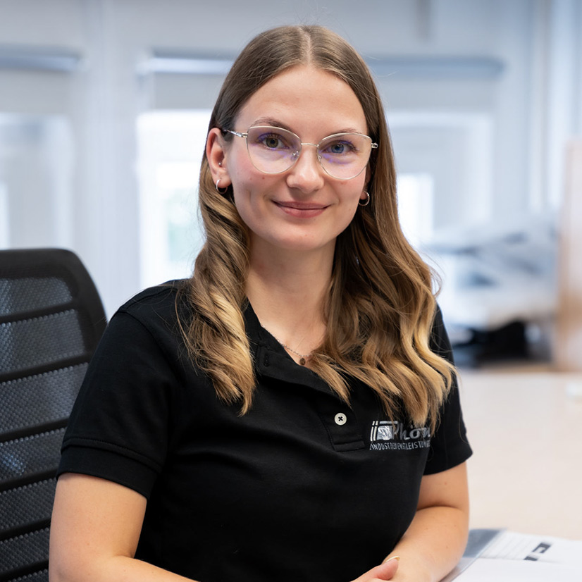 Eine Frau mit langen Haaren und Brille lächelt freundlich in die Kamera.
